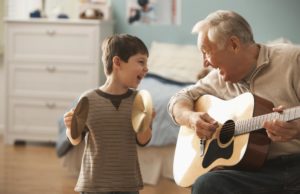 Caucasian man and grandson playing musical instruments together