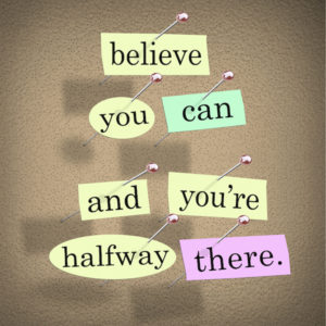 The saying Belive You Can and You're Halfway There on pieces of paper pinned to a bulletin board to symbolize belief, confidence, dedication and determination